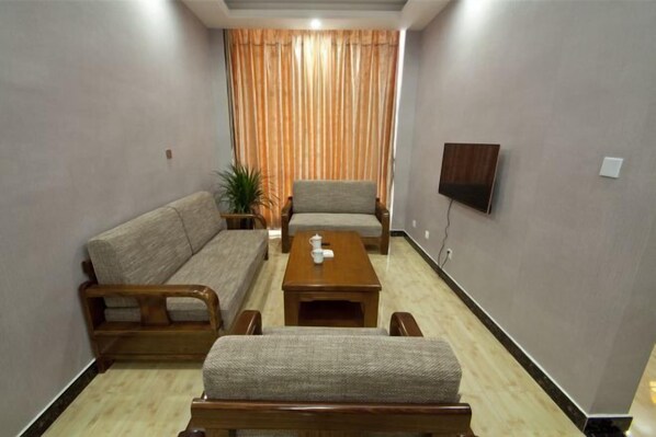 Una sala de estar con sofá, sillones, una mesa de centro y un televisor montado en la pared.