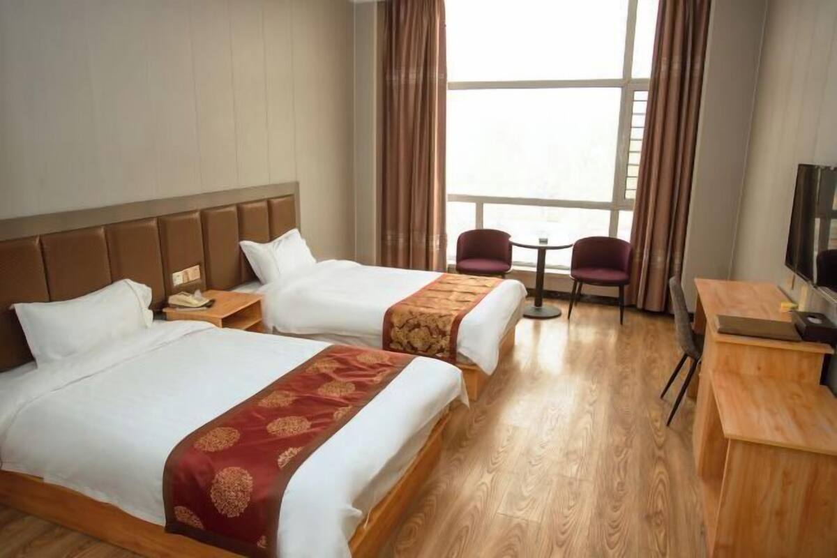 Una habitación de hotel con dos camas, un escritorio, una silla y un televisor.