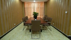 A conference room with a wooden table, brown chairs, and a potted plant. - Seven Hotels (Yinan)