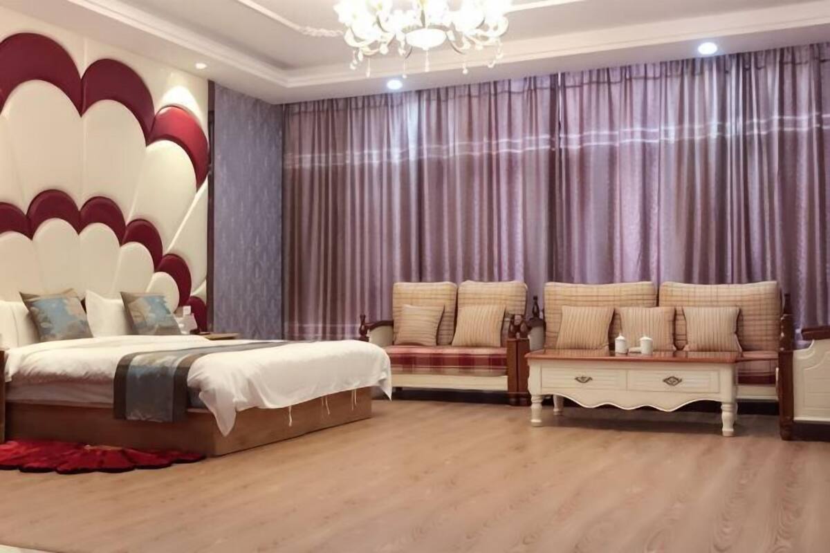 Un dormitorio con cama, sofá, mesita de noche y candelabro.