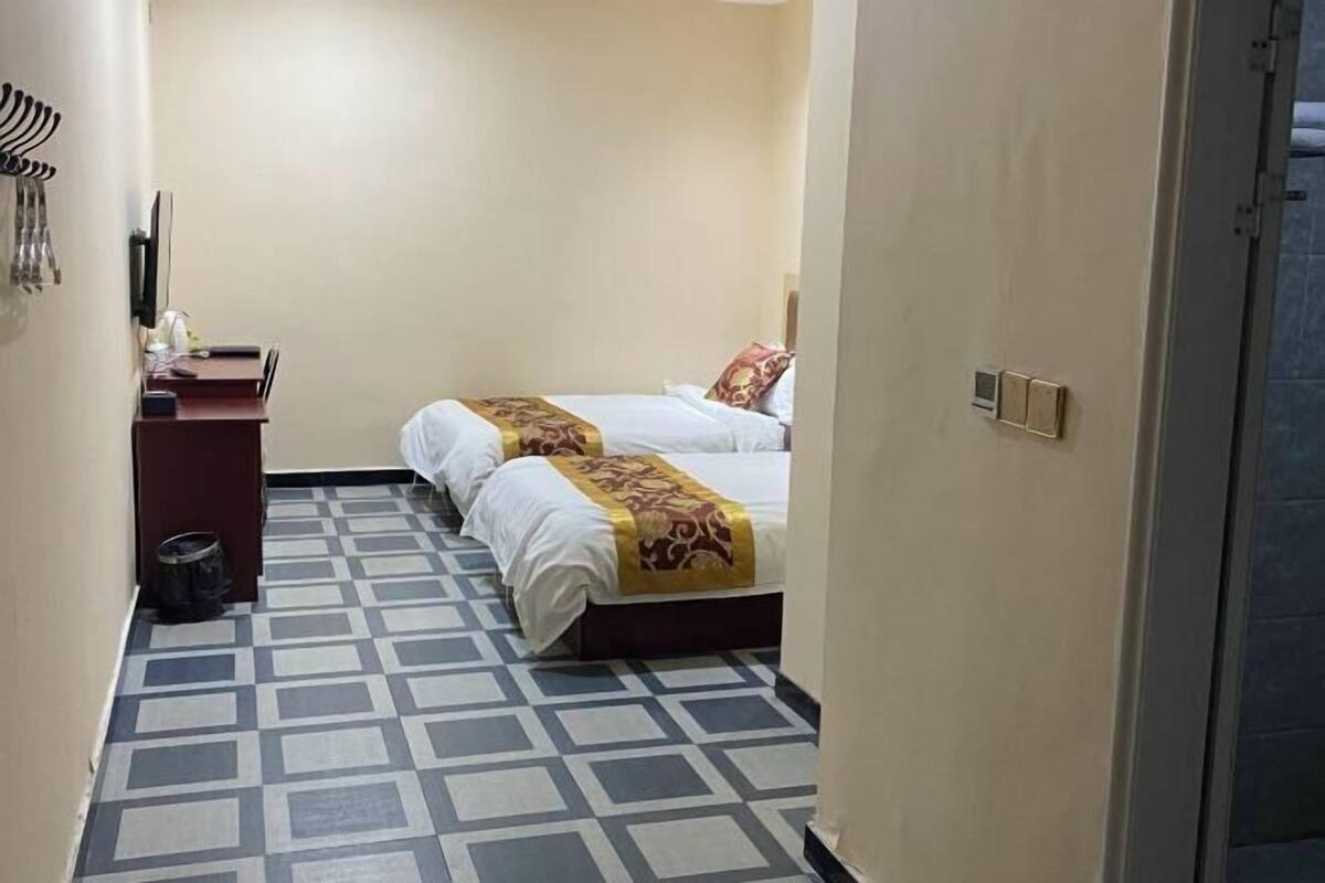 Una habitación de hotel con dos camas, un escritorio y un suelo con estampado.