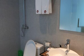 Un baño con lavamanos blanco, un espejo y una ducha.