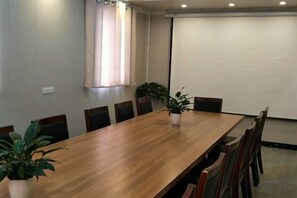 A conference room with a long wooden table, chairs, potted plants, and a projector screen. - " Liuba Landscape Hotel" (Liuba)