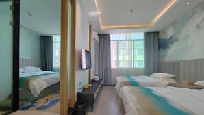 Een hotelkamer met twee bedden, een bureau, een spiegel en een televisie.