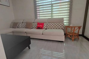 A living room with a sofa, a small table, and a window with blinds. - " Liuba Landscape Hotel" (Liuba)
