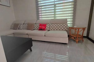 Una sala de estar con sofá, una mesita y una ventana con persianas.