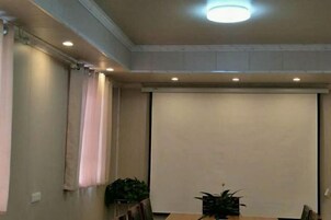 Un salón de conferencias con una pantalla de proyección, una mesa y sillas.