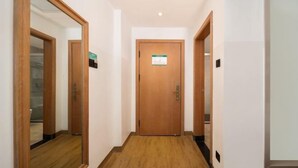 Ein Hotelgang mit Holzboden, einer Holztür und einem Spiegel auf der linken Seite.