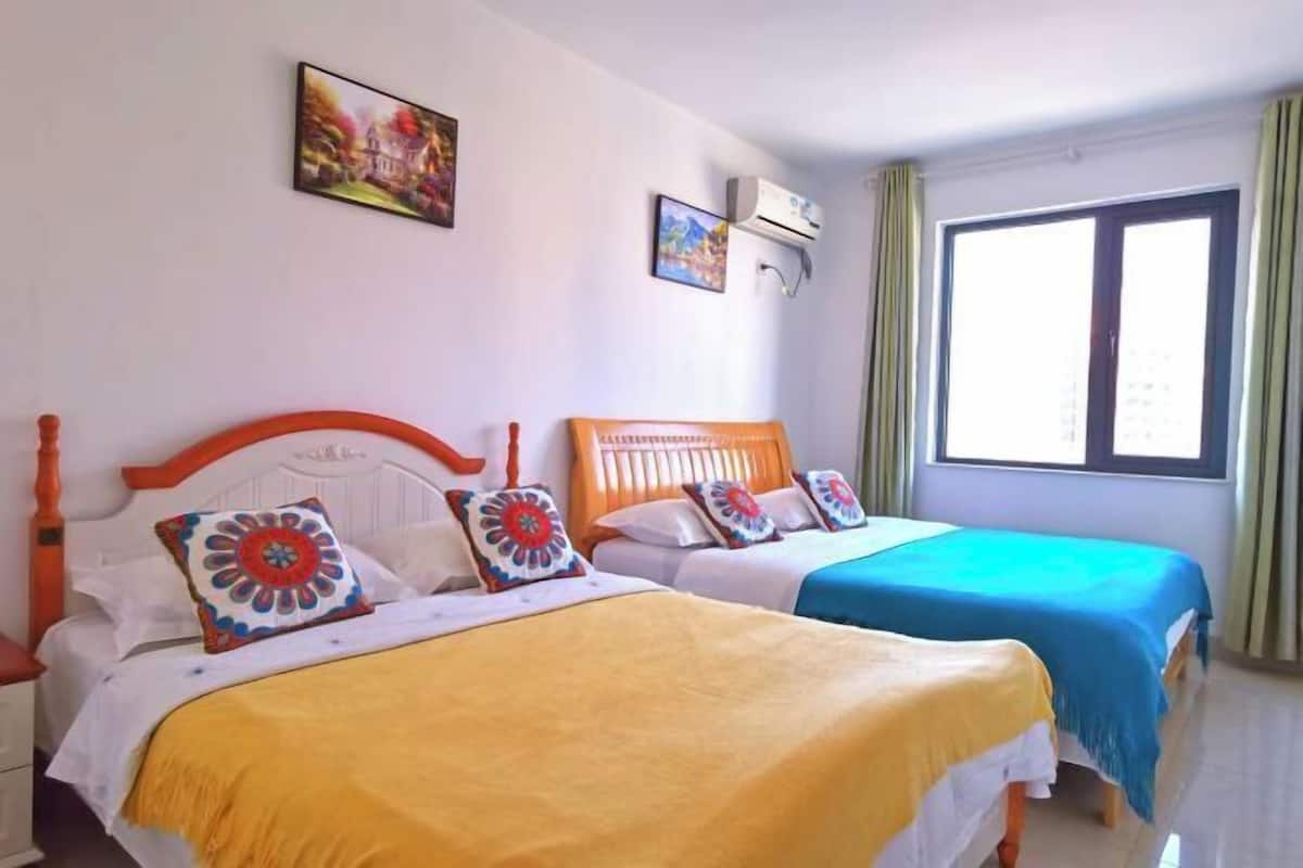 Een hotelkamer met twee bedden, elk met een verschillende dekbedovertrek, een wit hoofdbord en decoratieve kussens.