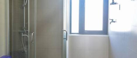 Un baño con cabina de ducha de vidrio, inodoro y ventana que proporciona luz natural.