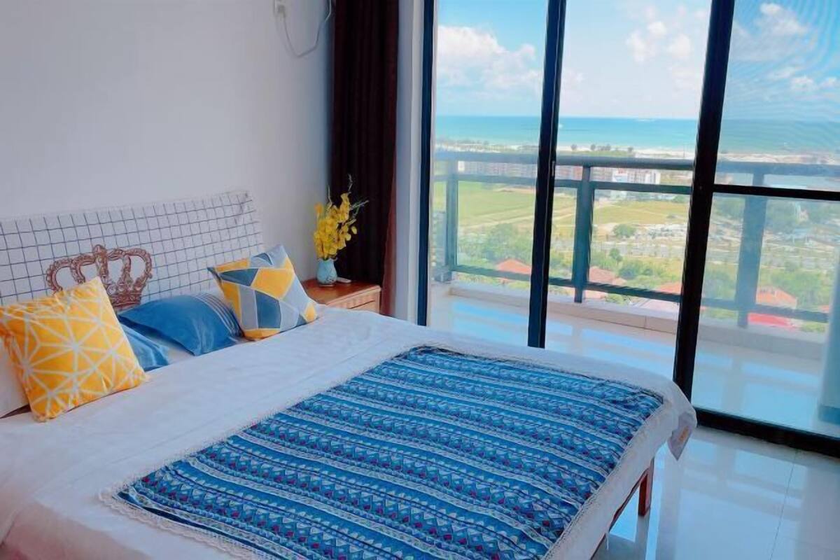 Een slaapkamer met een groot bed, uitzicht op de oceaan en een balkon.
