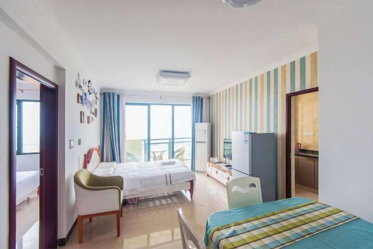 Een hotelkamer met een bed, een stoel, een bureau, een televisie en een kitchenette.