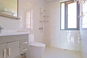 Een badkamer met toilet, wastafel, spiegel en douche.