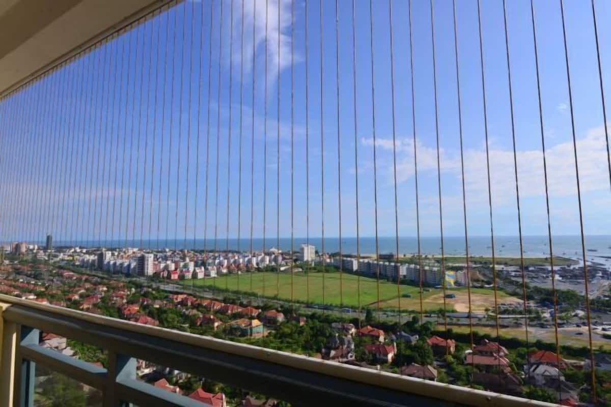 Varanda com vista para um horizonte costeiro, incluindo edifícios residenciais e um campo esportivo.