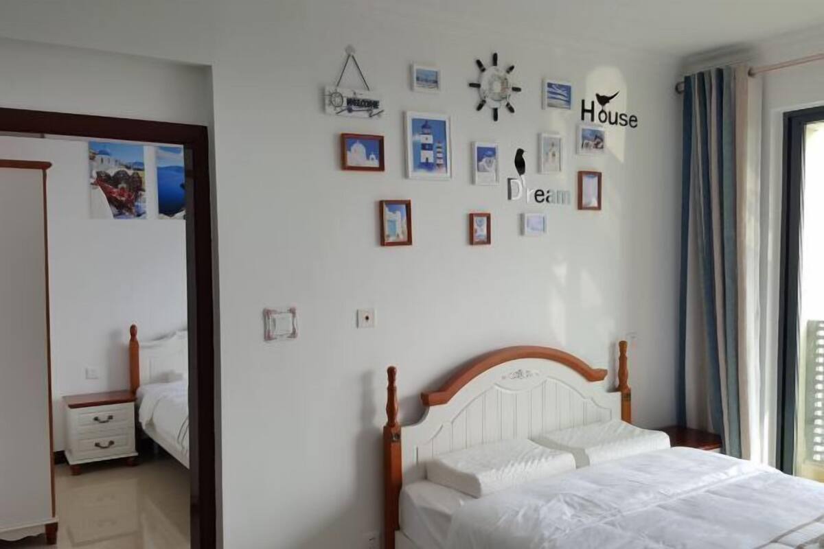 Een slaapkamer met een houten bed, een wandklok en afbeeldingen in lijsten.