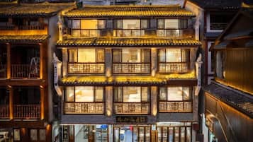 Un edificio tradicional de varios pisos con patio interior, balcones de madera y ventanas iluminadas.