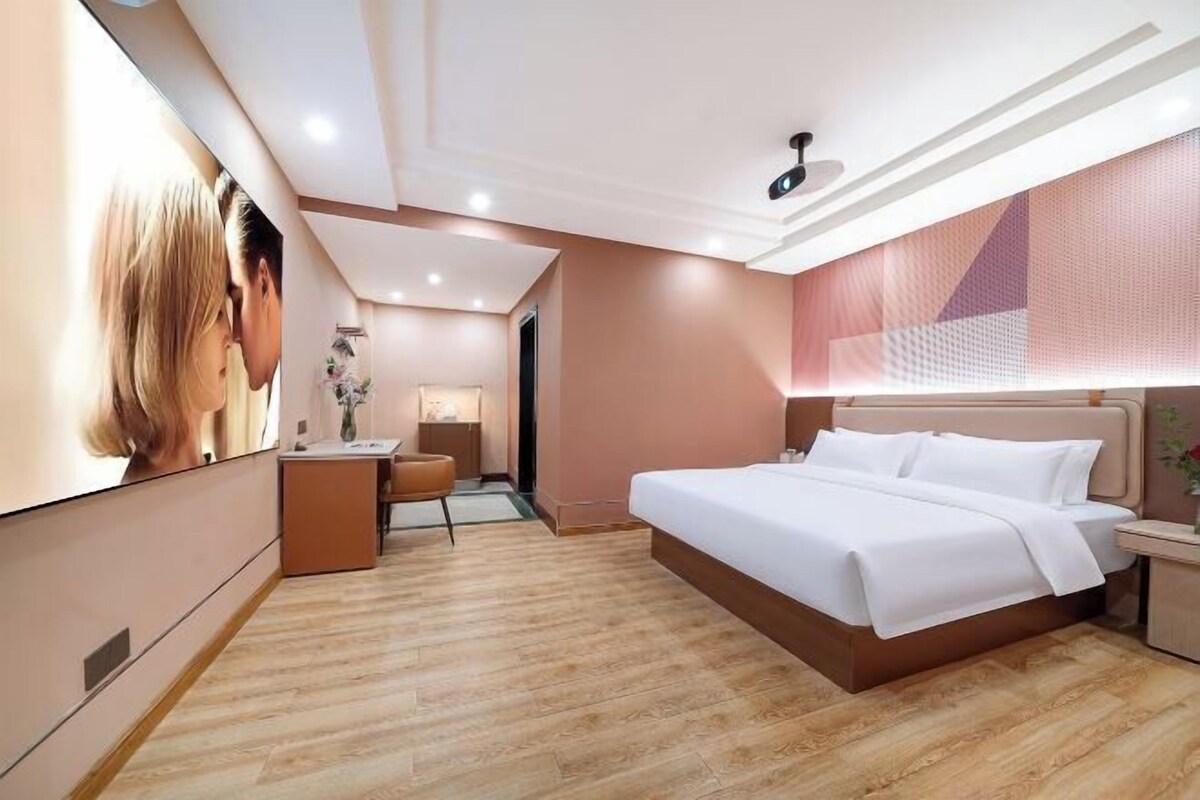 A hotel room with a large bed, bedside tables, a desk, and a mirror.