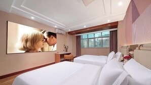 A hotel room with two beds, a large mirror, a desk with a chair, and a window with a view.