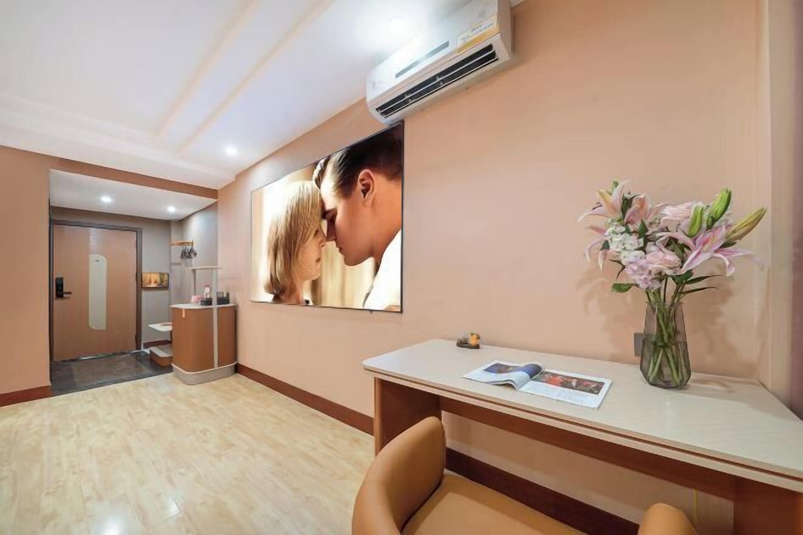 Zona de recepción de un hotel con un mostrador, un área de espera y un espejo que refleja a una pareja.