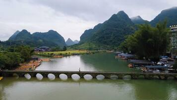 A river with a bridge, mountains in the background, and a building on the right.