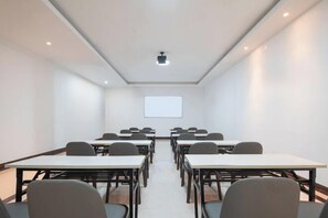 Un salón de conferencias con mesas y sillas dispuestas para reuniones.