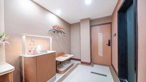 A hotel corridor with a reception desk, a seating area, and a door leading to a room.