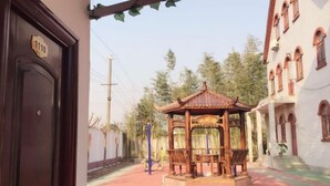 Un quiosco de madera tradicional en un patio con un edificio blanco al fondo.