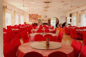 A large dining hall with round tables covered in red tablecloths and red chairs. - Beihu Bay Resort (Shanghai)