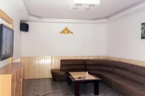 A living room with a brown sofa, a small table, a television, and a decorative wall piece. - Beihu Bay Resort (Shanghai)