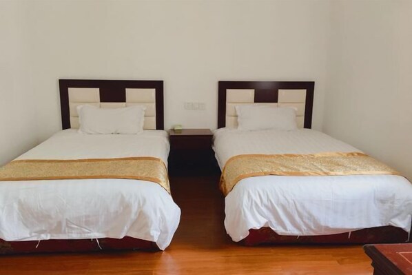 A room with two single beds, wooden headboards, white bedding, and a wooden floor. - Beihu Bay Resort (Shanghai)