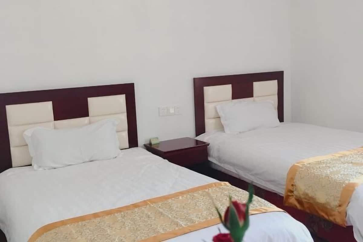 A hotel room with two beds, each with a wooden headboard and white bedding.