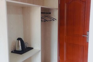 A room with a wooden wardrobe, a red door, and a shelf with a kettle and a glass jar. - Beihu Bay Resort (Shanghai)