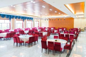 A banquet hall with multiple round tables and chairs, large windows, and a wooden ceiling. - Jingbian Danxia Tourism Resort (Jingbian County)
