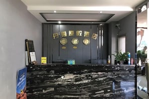 A reception area with a marble counter, a clock, and a sign with Chinese characters. - Jingbian Danxia Tourism Resort (Jingbian County)