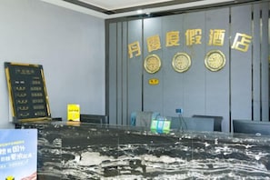A reception area with a black marble counter, a wall clock, and a signboard. - Jingbian Danxia Tourism Resort (Jingbian County)