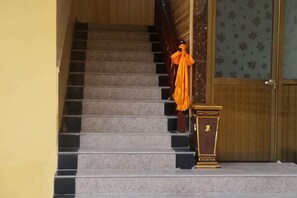 A staircase leading to a room with a wooden door and a patterned wall. - Niegan Dawa Hotel (Diebu)