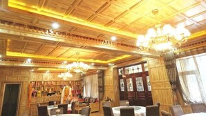 A hotel lobby with wooden paneling, chandeliers, and a bar area. - Niegan Dawa Hotel (Diebu)