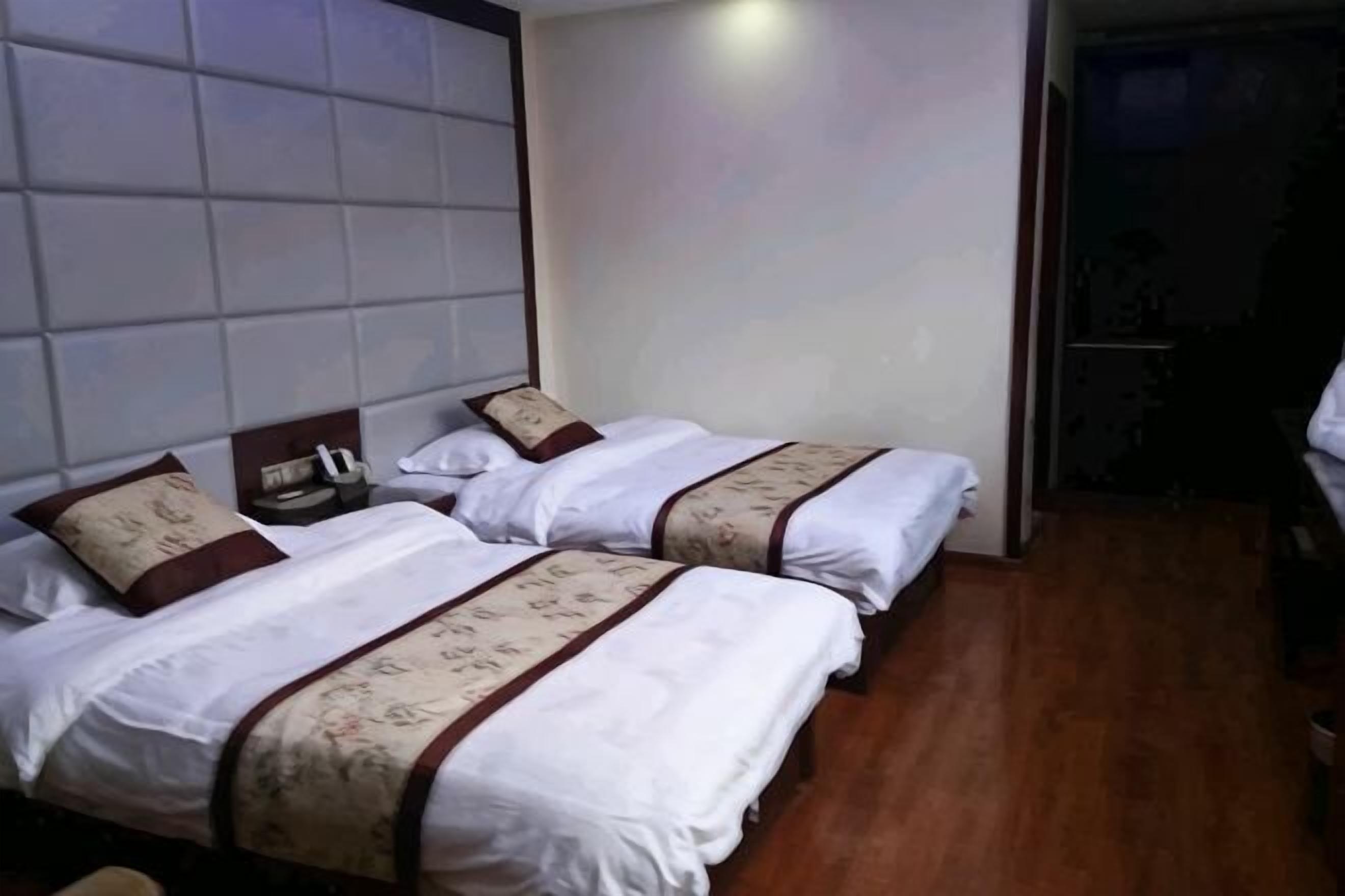 A hotel room with two beds, a headboard, and a nightstand.