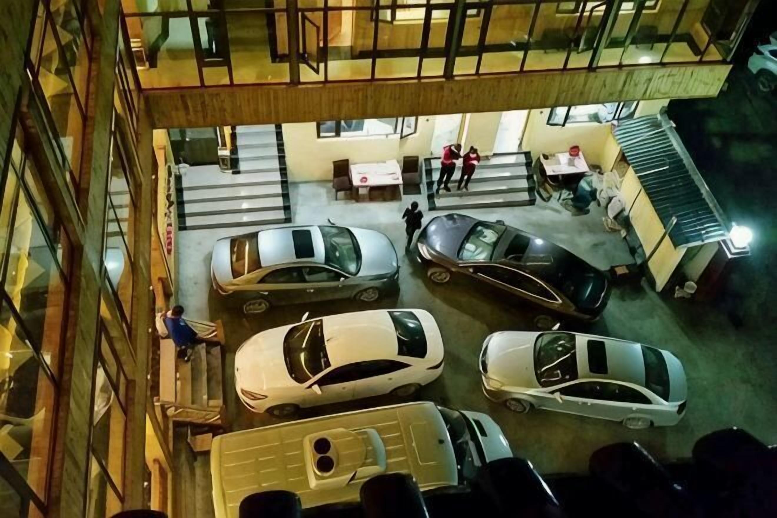 An indoor parking area with multiple cars and a staircase leading to an upper level.