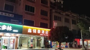 A hotel with a prominent sign, a glass entrance, and a building facade with multiple windows. - Xinjingtai Hotel Xing'an (Xing'an County)
