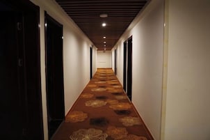 Un pasillo de hotel con alfombra estampada, puertas a ambos lados y un techo con iluminación empotrada.