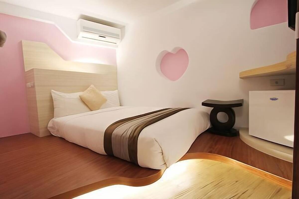 A bedroom with a bed, bedside table, and a wall-mounted air conditioner.