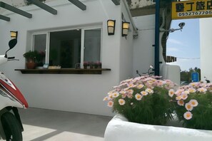 A white building with a window, a potted plant, and a flower bed. - Kenting Hostel（Villa） (Pingtung)