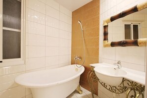 Une salle de bain avec une baignoire, un lavabo, une douche et un miroir.