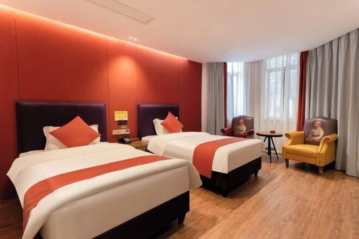 A hotel room with two beds, a small table, a chair, and a sofa.