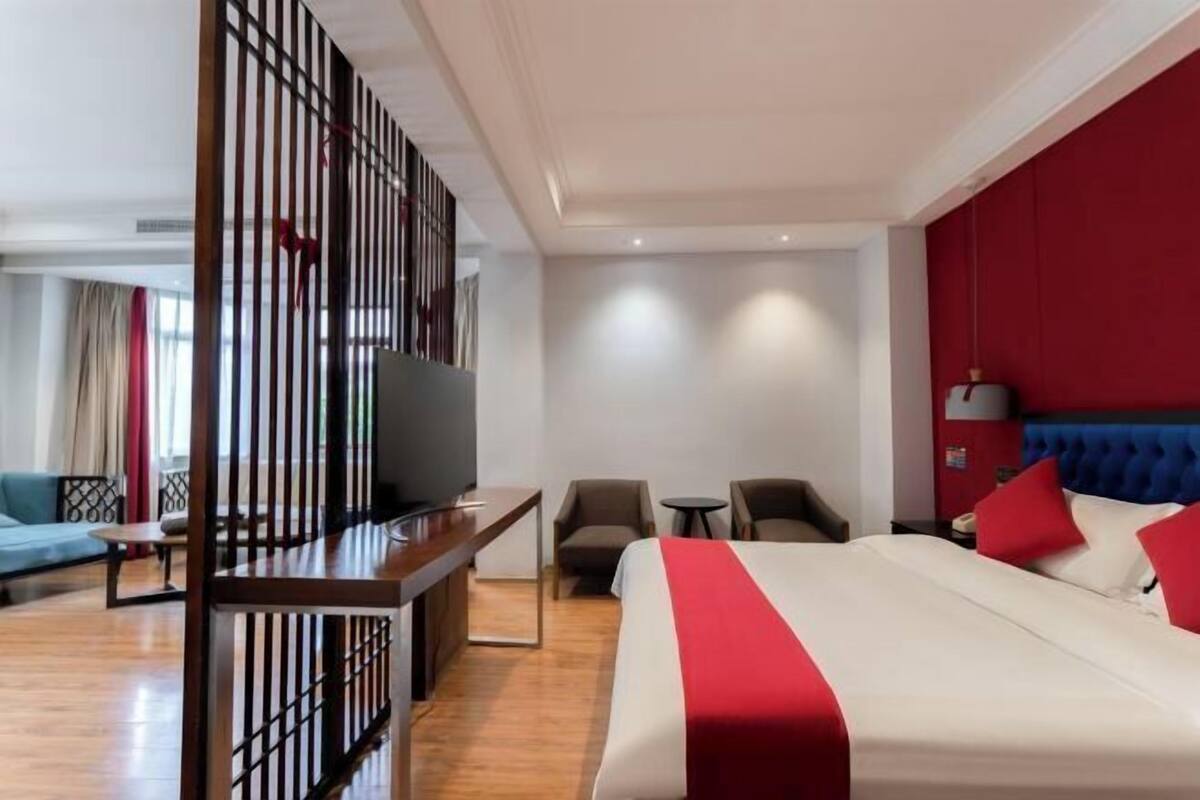 A hotel room with a bed, a TV, a desk, a chair, and a sofa.