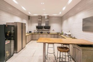 Une cuisine moderne dotée d’appareils électroménagers en acier inoxydable, d’un plan de travail en bois et de tabourets de bar.