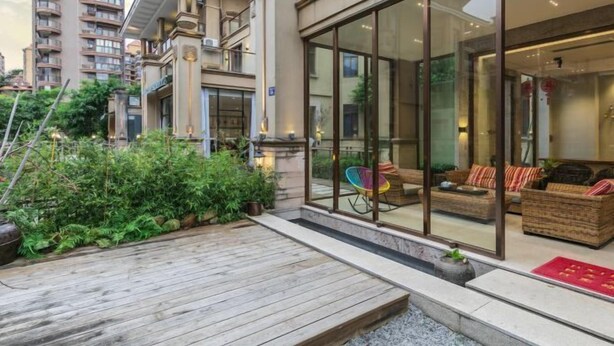 Un bâtiment moderne doté d’une façade en verre, d’un espace extérieur aménagé pour s’asseoir et d’une terrasse en bois.