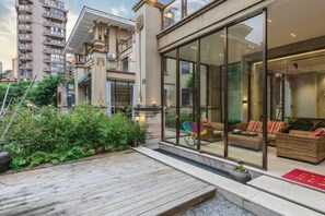 Un edifici modern amb façana de vidre, zona d'estar a l'aire lliure i terrassa de fusta.
