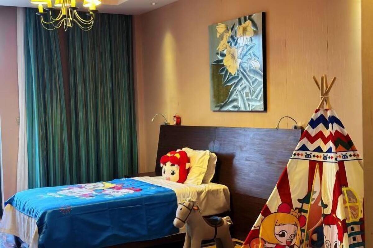 Quarto de hotel com cama, pintura, candelabro e decoração tipi.